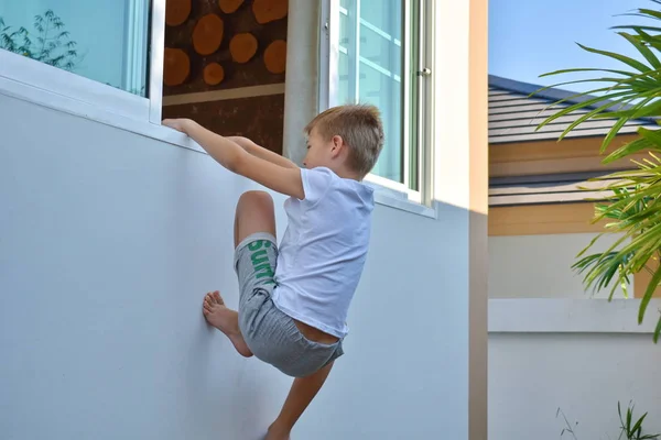 Anak itu memanjat keluar jendela yang terbuka. Anak itu memanjat ke dalam ruangan. — Stok Foto