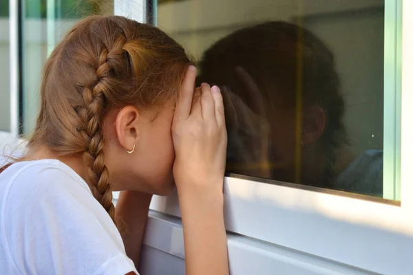 Mała dziewczynka podgląda przez okno. Dziecko dziewczyna patrząc przez okno — Zdjęcie stockowe