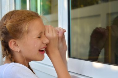 A girl Peeps through the window. Voyeurism. Children's curiosity. clipart