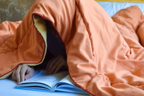 Девушка читает книгу под одеялом. Ребенок читает в постели . — стоковое фото