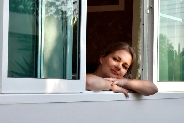 Menina bonita olha para fora da janela aberta. Publicidade de novas janelas . — Fotografia de Stock