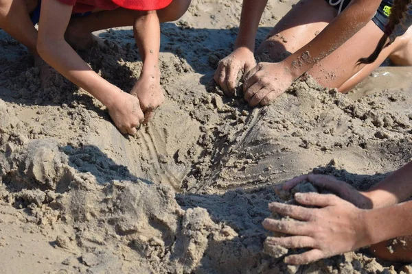 Gyerekek ástak a homokgödörben. Játékok a tenger partján. Szórakoztató gyerekek, akik kincset keresnek. Tengeri játékok tengerpartja. — Stock Fotó