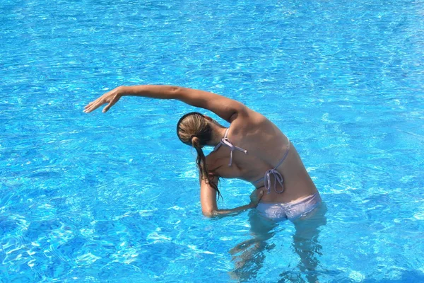 Esercizi in piscina. Ragazza che fa esercizi in piscina. uno sport attivo. bella donna in costume da bagno in acqua formazione — Foto Stock