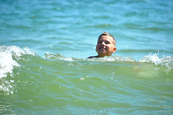 Ragazzo bambino nuotare in mare. Un ragazzo nuota nell'oceano aperto. Imparare a nuotare nel mare salato. Vacanze estive ai tropici . — Foto Stock