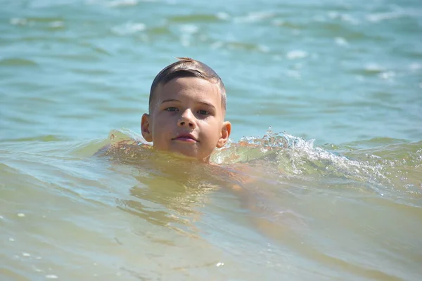 Ragazzo bambino nuotare in mare. Un ragazzo nuota nell'oceano aperto. Imparare a nuotare nel mare salato. Vacanze estive ai tropici . — Foto Stock