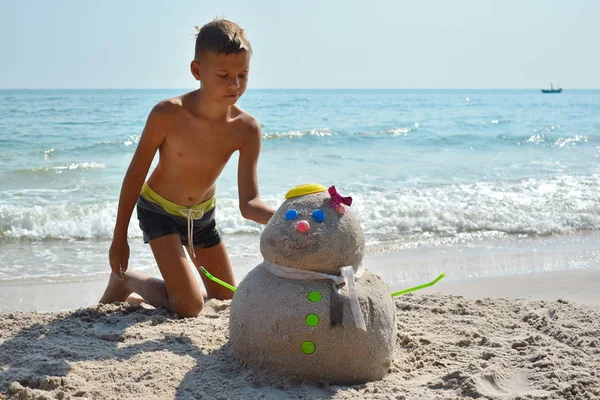 Pojken gör snögubben på havet. Glad vinter i Thailand. Vintersemester till havs. Nytt år på ön. — Stockfoto