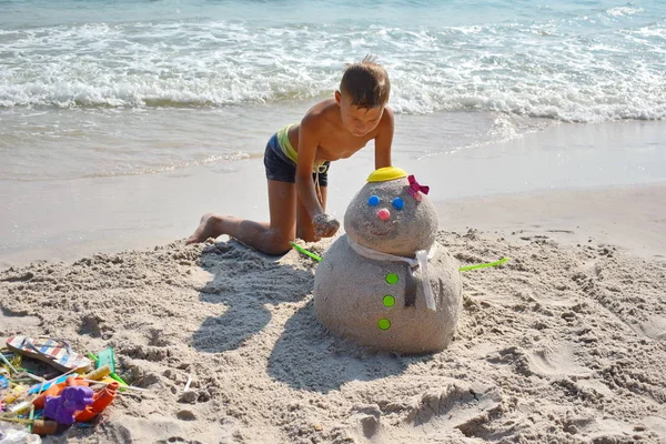 Chłopiec robi Sandmana na plaży. Dziecko buduje bałwana na plaży. Nowy rok na tropikalnym oceanie. — Zdjęcie stockowe