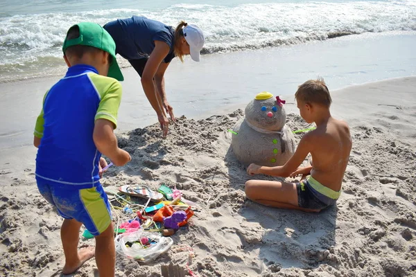 Chłopcy robią Sandmana na plaży. Dziecko buduje bałwana na plaży. Nowy rok na tropikalnym oceanie. — Zdjęcie stockowe