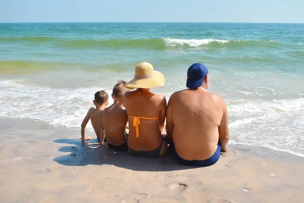Family sitting on the sand on the beach. Family holidays by the sea. Happy children and parents on vacation in the tropics. — 스톡 사진