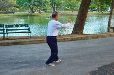 Tayland. Bangkok 'ta. Ocak 2020. Parkta qigong egzersizi yapan Asyalı bir erkek. Çinliler halka açık bir yerde qigong oynuyorlar.. 