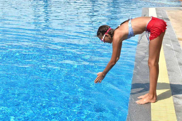 Dziewczynka wskakuje do basenu. Dziewczyna uczy się pływać autdoor. Basen w hotelu. Dzieci pływają w odkrytym basenie. — Zdjęcie stockowe