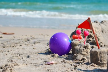 Kumsaldaki kumdan kale. Çocuklar deniz üzerinde bir şehir inşa ettiler. Sahilde çocuk oyuncakları. Çocuklu deniz aileleri. 