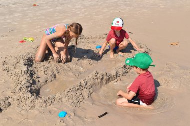  Çocuklar kumlu plajda birlikte oynuyorlar. Denizde bir tatil köyü.. 