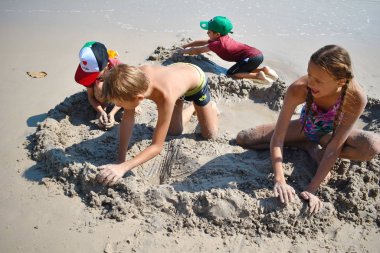 . Çocuklar kumlu plajda birlikte oynuyorlar. Denizde bir tatil köyü.. 