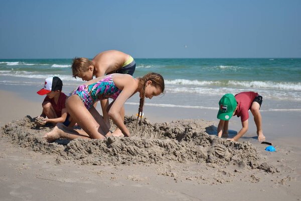 . Children play together on the sandy beach. Children's resort on the sea. 