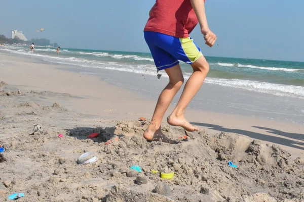 Trampling feet sand. Little boy breaks a sand castle. The child treads the construction on the beach. Angry Child boy at sea. — 스톡 사진