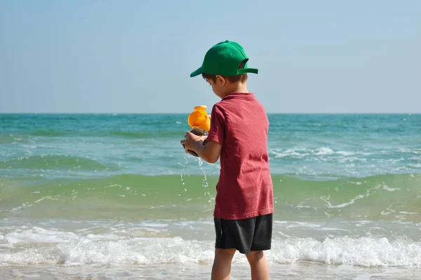 Pojkbarn leker i havet. Barnstänk i vattenautomaten. Din semester till sjöss. Spel i havet. — Stockfoto