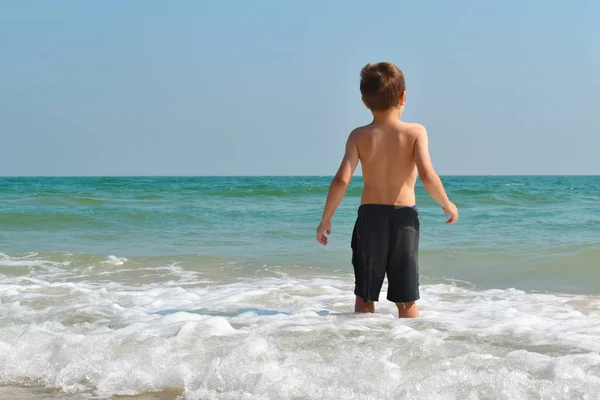 Pojkbarn leker i havet. Barnstänk i vattenautomaten. Din semester till sjöss. Spel i havet. — Stockfoto