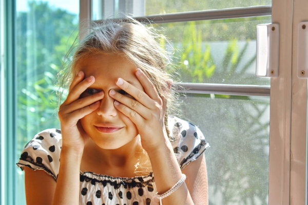 Cute child girl peeking. Beautiful girl peeping. The Sly glance of the child. The child spies. Hide-and-seek.