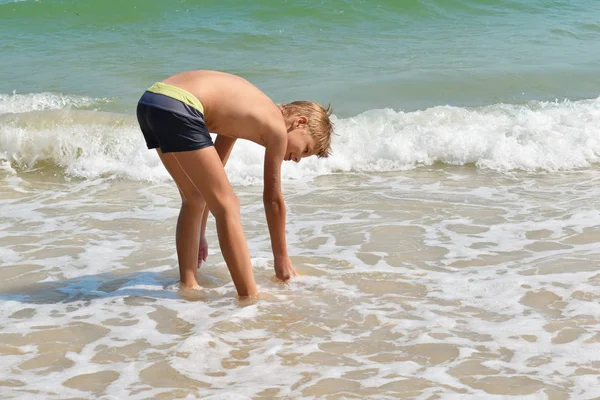 Pojkbarn leker i havet. Barnstänk i vattenautomaten. Din semester till sjöss. Spel i havet. — Stockfoto