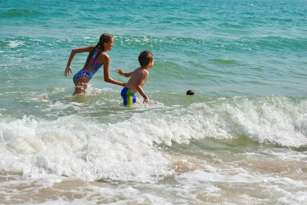 Roliga ungar som leker i havet. Pojkarna plaskar i havsvatten. Familjesemester i tropikerna. Barn leker i havet. — Stockfoto