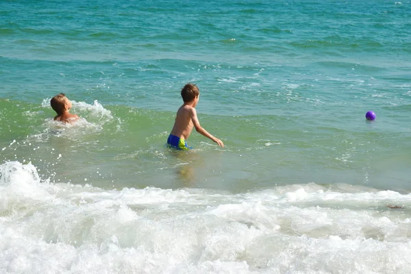 Roliga ungar som leker i havet. Pojkarna plaskar i havsvatten. Familjesemester i tropikerna. Barn leker i havet. — Stockfoto