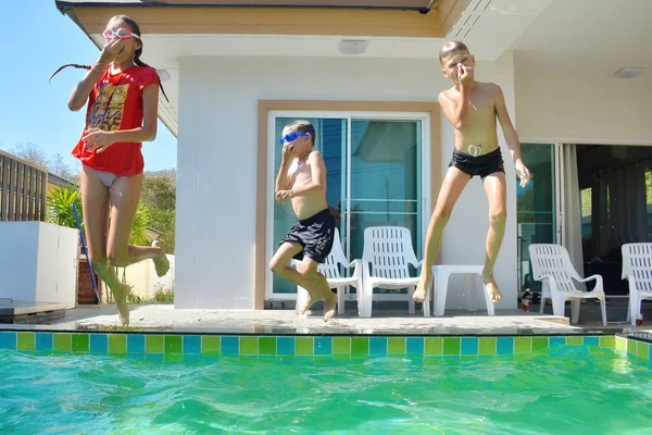 Grupa dzieci skaczących do basenu. Szczęśliwe dzieci nurkować w prywatnym basenie w domu. Wakacje w ośrodku. — Zdjęcie stockowe