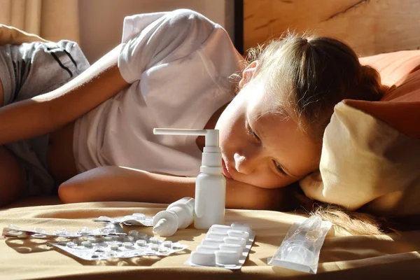 Ziek meisje in bed. Een klein meisje met pijn. Het kind drinkt veel medicijnen.. — Stockfoto