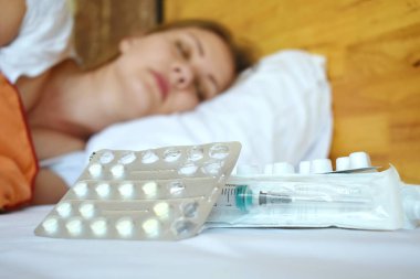 Hasta kadın ilaçla yatıyor. Evde hasta kalmak ve hap almak için. Soğuk algınlığı. Geleneksel tıp.