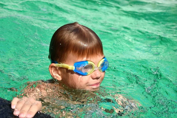 Menino numa piscina azul no hotel. Criança nada em óculos — Fotografia de Stock