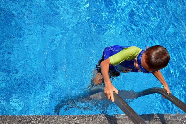 Menino numa piscina azul no hotel. Criança nada em óculos — Fotografia de Stock