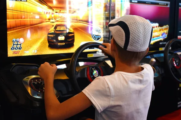 Simulador de coches de carreras. Un niño pequeño juega juegos virtuales. De carreras de computadoras. —  Fotos de Stock