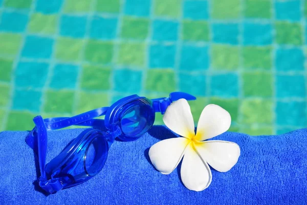 Óculos de natação em uma toalha junto à piscina. Férias tranquilas de luxo no resort à beira-mar. bela piscina no hotel . — Fotografia de Stock