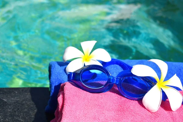 Óculos de natação em uma toalha junto à piscina. Férias tranquilas de luxo no resort à beira-mar. bela piscina no hotel . — Fotografia de Stock