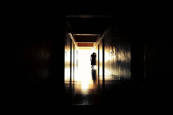 光と不気味な廊下。悲観的なトンネルだ家の廊下に小さな女の子の幽霊。古い家の中の幽霊. — ストック写真