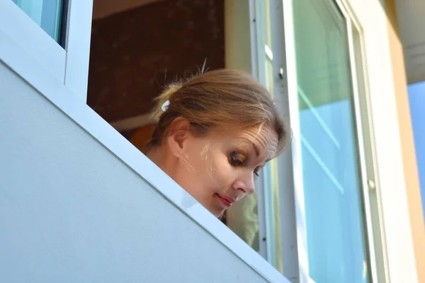 La mujer mira hacia abajo. Cabeza femenina en la ventana . — Foto de Stock
