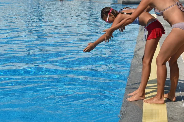 母は娘をプールで訓練する。女の子がボードからプールに飛び込む. — ストック写真