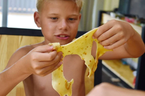 Ein Kind spielt mit Essen. Traditionelle russische Pfannkuchen. — Stockfoto