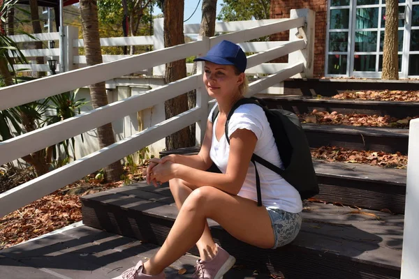 El prestigioso viaje solitario. excursionista chica sentada alrededor de la casa. Mujer con mochila sentada en las escaleras. —  Fotos de Stock