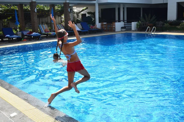 女孩在度假胜地的室外游泳池里跳. — 图库照片