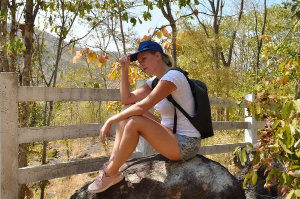 Chica excursionista sentada en una gran piedra. El viajero se sienta descansando en la montaña. — Foto de Stock