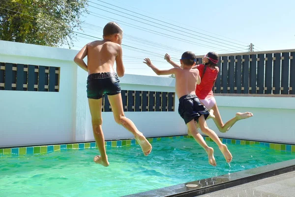 Grupa dzieci skaczących do basenu na bok. Zabawa dzieci w basenie w lecie — Zdjęcie stockowe