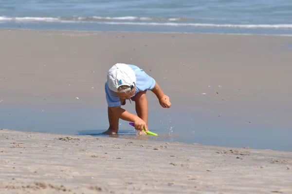 Ein kleines Kind spielt den Tag im Sand am Strand. — Stockfoto