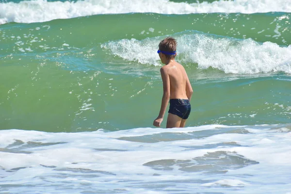 Niño saltando sobre olas marinas. Niño feliz en el océano . — Foto de Stock