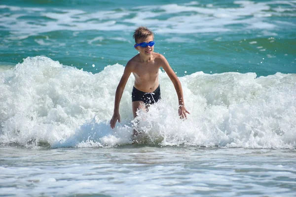 Niño saltando sobre olas marinas. Niño feliz en el océano . — Foto de Stock