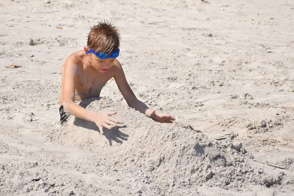 Мальчик на пляже играет. Ребенок в стаканах воды на море . — стоковое фото