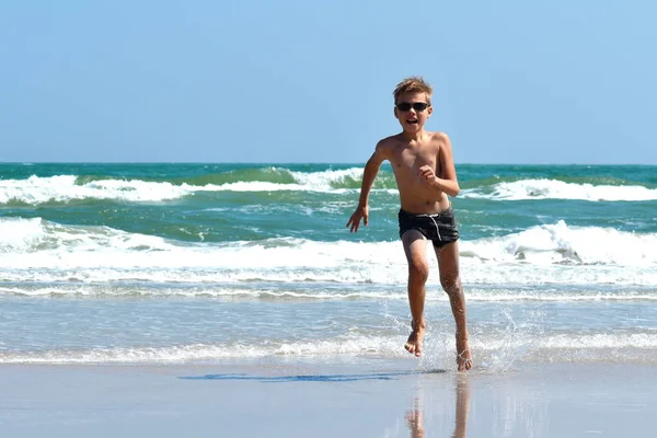 Een kind dat op zee springt. Gelukkig kind in de oceaan. — Stockfoto