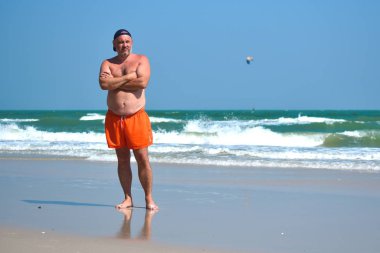 Adam deniz kıyısında yürüyor. Denizin kenarında bir sabah yürüyüşü.