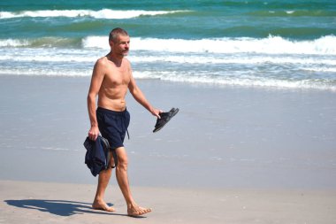 Adam deniz kıyısında yürüyor. Denizin kenarında bir sabah yürüyüşü.