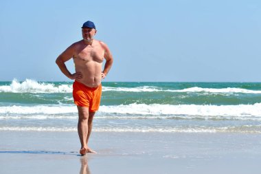 Adam deniz kıyısında yürüyor. Denizin kenarında bir sabah yürüyüşü.